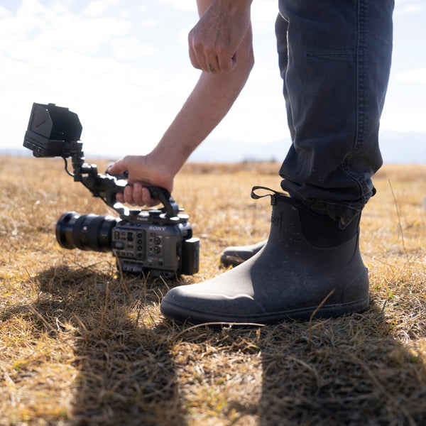 Person filming in a field with a camera and stabilizer