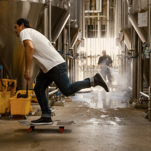 Person skateboarding inside a industrial setting with large tanks and equipment.
