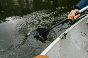Tattooed hand on boat oar in side of canoe